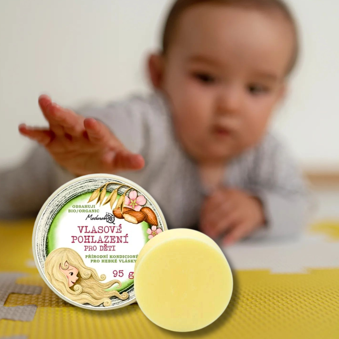 Baby reaching toward Medarek Children’s Hair Balm—solid conditioner bar and tin in the foreground.